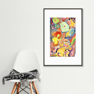 abstract colorful floral art print in black frame hanging on wall above white chair