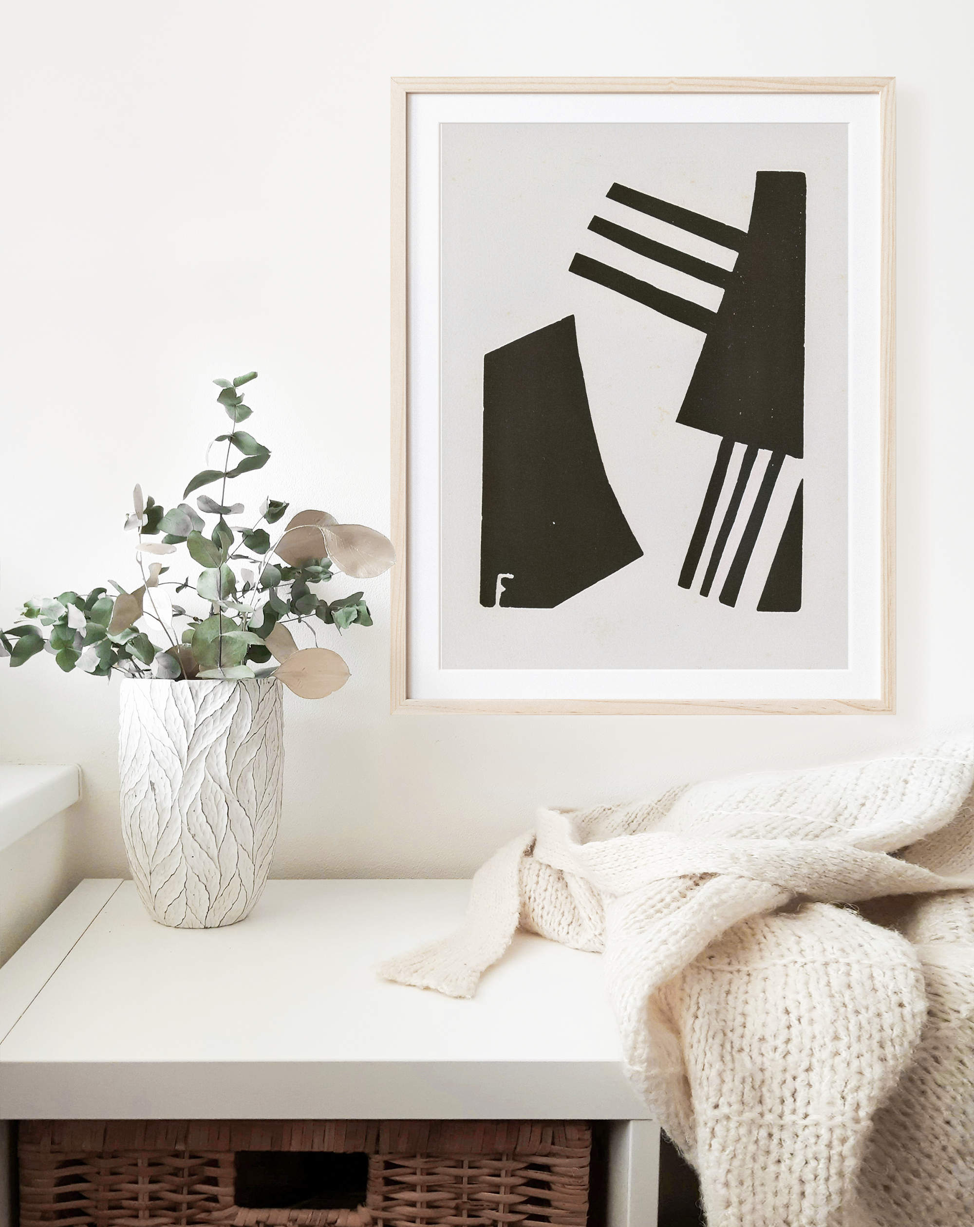 black and white abstract art hanging in natural wood frame on wall