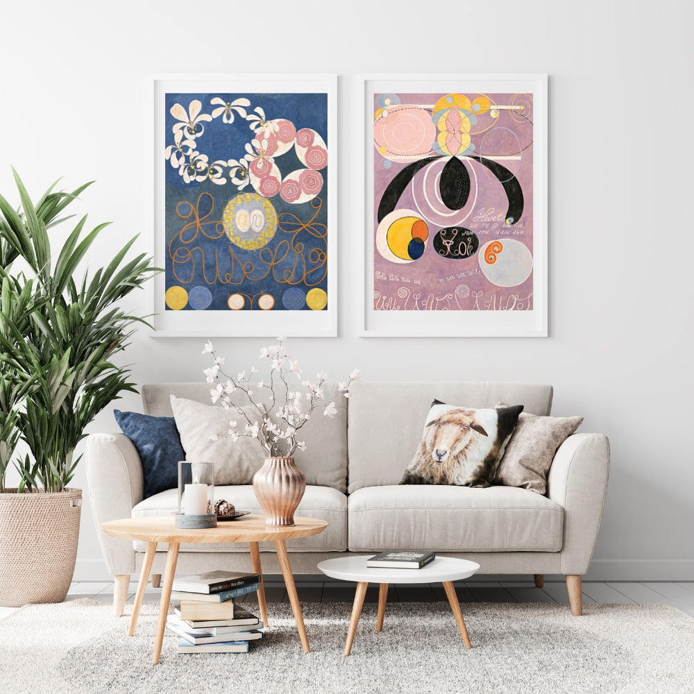 abstract art poster in mostly blue next to one in mostly pink by artist Hilma af Klint hanging on wall above sofa